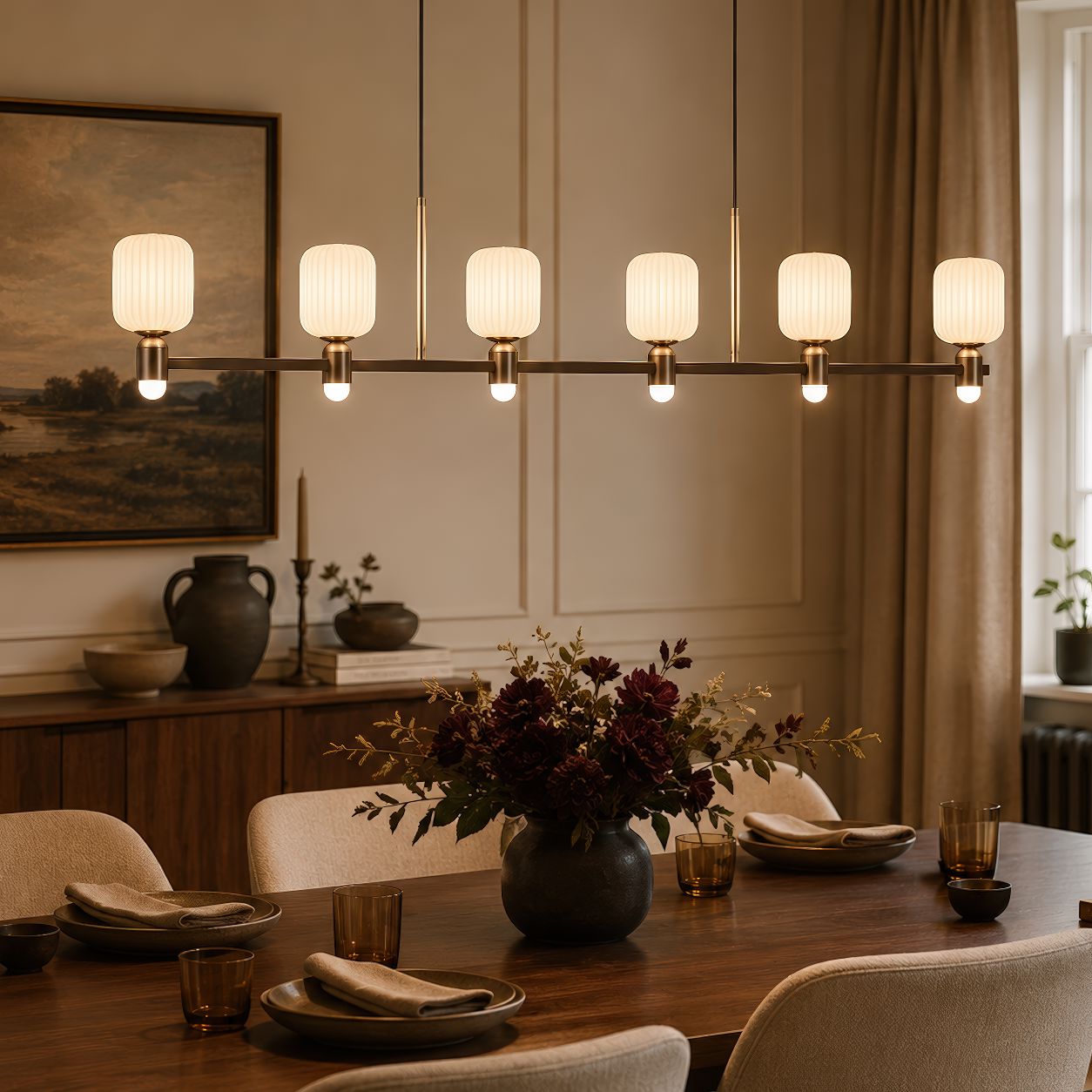 linear bronze chandelier above a dining table with dark flowers